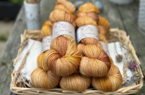 Five skeins of yarn in gently variegated shades of gold, brown, and yellow. 
