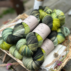 Five skeins of variegated yarn in shades of green from light to dark. 