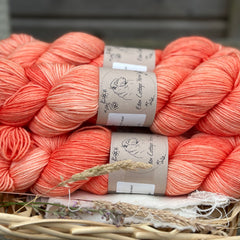 Five skeins of hand-dyed semi-solid coral yarn.