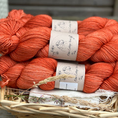 Five skeins of hand dyed semi-solid orangey red yarn. 