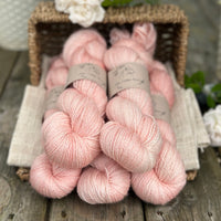 five skeins of hand dyed yarn in a light warm coral colour