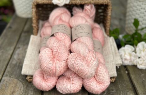 five skeins of hand dyed yarn in a light warm coral colour