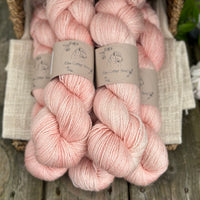 five skeins of hand dyed yarn in a light warm coral colour