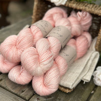 five skeins of hand dyed yarn in a light warm coral colour