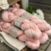 five skeins of hand dyed yarn in a light warm coral colour