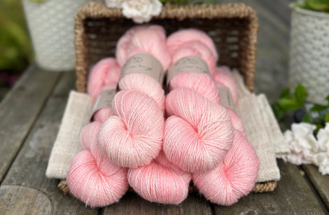 five skeins of hand dyed yarn in a soft pinkish coral colour