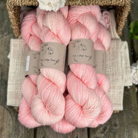 five skeins of hand dyed yarn in a soft pinkish coral colour