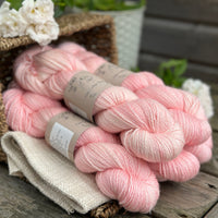 five skeins of hand dyed yarn in a soft pinkish coral colour