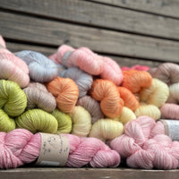 heaps of skeins of hand dyed yarn on a wooden garden bench