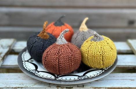 Four knitted pumpkins on a plate