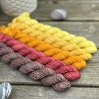 Five mini skeins of yarn in a fade from brown to yellow