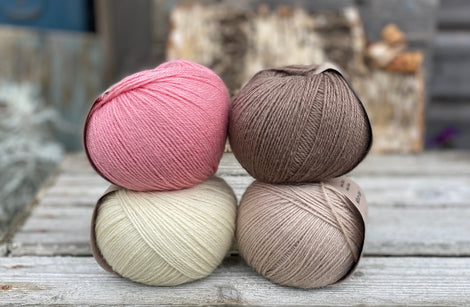 Four balls of yarn. Colours are natural cream, beige, pink and brown