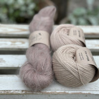 A skein of fluffy beige yarn with two balls of beige yarn