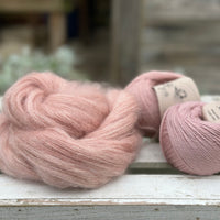 A swirl of fluffy pink yarn with two balls of pale pink yarn