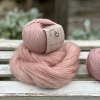 A swirl of fluffy pink yarn with two balls of pale pink yarn