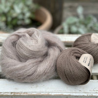 A swirl of brown fluffy yarn alongside two balls of brown yarn