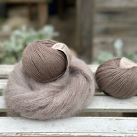 A swirl of brown fluffy yarn with two balls of brown yarn