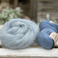 A swirl of fluffy pale blue yarn with two balls of blue yarn