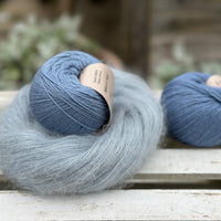 A swirl of fluffy pale blue yarn with two balls of blue yarn