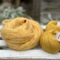 A swirl of fluffy yellow yarn with two balls of yellow yarn