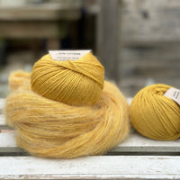 A swirl of fluffy yellow yarn with two balls of yellow yarn