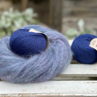 A swirl of fluffy blue yarn with two balls of dark blue yarn