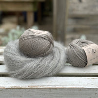 A swirl of fluffy grey yarn with two balls of grey yarn