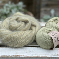 A swirl of fluffy green yarn alongside two balls of pale green yarn