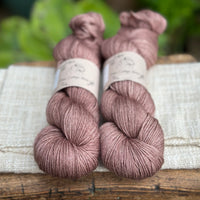 Two skeins of hand dyed yarn in a soft rosy brown shade.