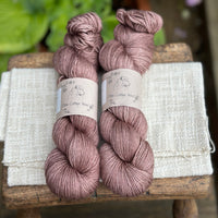 Two skeins of hand dyed yarn in a soft rosy brown shade.