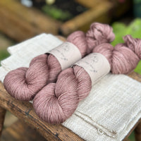 Two skeins of hand dyed yarn in a soft rosy brown shade.