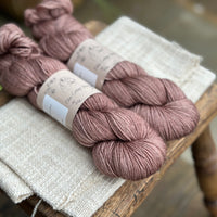 Two skeins of hand dyed yarn in a soft rosy brown shade.