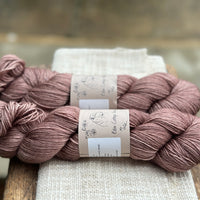 Two skeins of hand dyed yarn in a soft rosy brown shade.