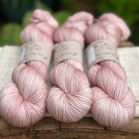 three skeins of hand dyed yarn in a soft slightly earthy pink shade.