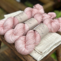 three skeins of hand dyed yarn in a soft slightly earthy pink shade.