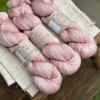 three skeins of hand dyed yarn in a soft slightly earthy pink shade.