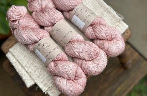 three skeins of hand dyed yarn in a soft slightly earthy pink shade.