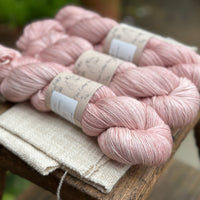 three skeins of hand dyed yarn in a soft slightly earthy pink shade.